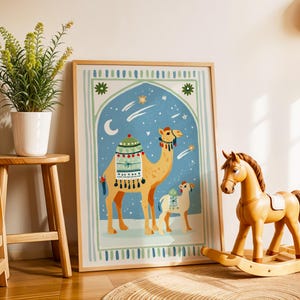 May include: A framed art print featuring two camels in a desert scene with a blue sky, stars, and a crescent moon. The artwork is in a wooden frame and is displayed next to a wooden rocking horse and a potted plant.