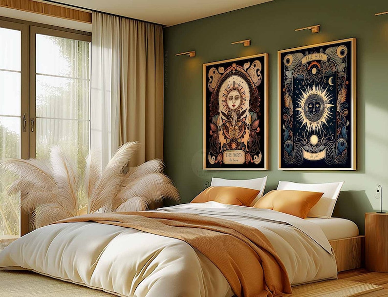 May include: Two framed illustrations of the sun and moon with intricate details and a dark background. The frames are hanging on a sage green wall above a bed with a white duvet and a brown throw blanket.