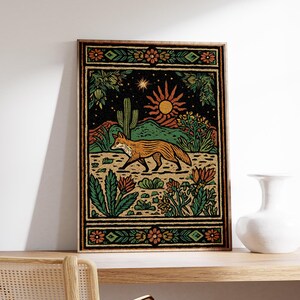 May include: A framed art print featuring a desert landscape with a fox. The artwork has a black background with a sun, cactus, and various plants. The fox is orange and brown, and the frame is brown.