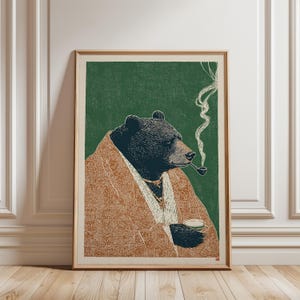 Puede incluir: Lámina artística enmarcada que representa un oso con una túnica marrón, fumando en pipa y sosteniendo una taza. El fondo es verde. El arte tiene un estilo vintage de xilografía.