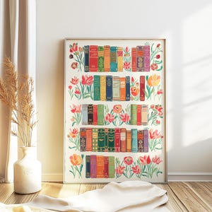 Könnte beinhalten: Ein weißer gerahmter Druck mit einer farbenfrohen Illustration eines Bücherregals voller Bücher und Blumen. Die Bücher haben bunte Rücken und sind in Reihen angeordnet. Die Blumen sind in den Farben Rosa, Rot, Orange und Gelb.