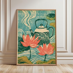 Op de afbeelding: Een ingelijste print met een groenblauwe achtergrond, een witte theepot met opstijgende stoom, omringd door twee grote koraalkleurige lotusbloemen en groene waterleliebladeren. Het kunstwerk heeft een gestructureerde blokdrukstijl.