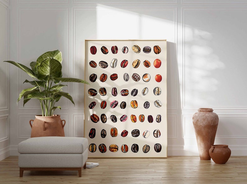 May include: A framed print of a coffee bean illustration. The print features a grid of coffee beans in various shades of brown, red, and white. The print is framed in a gold frame and is hanging on a white wall.