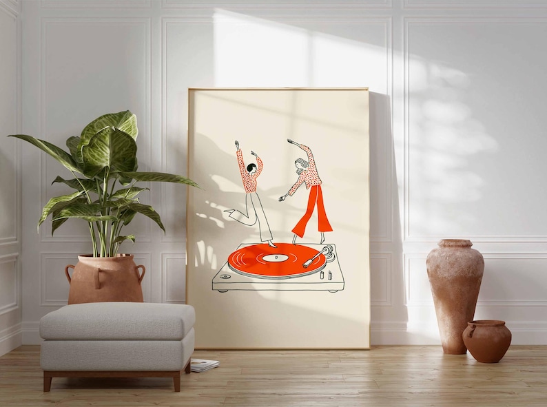 Puede incluir: Una impresi&oacute;n art&iacute;stica enmarcada representa a dos figuras bailando sobre un tocadiscos. Las figuras visten camisas y pantalones de lunares rojos y blancos. El tocadiscos tiene un disco de color naranja brillante. La impresi&oacute;n se exhibe en una habitaci&oacute;n con una planta y un taburete.