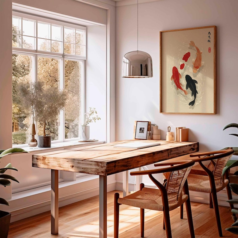 Puede incluir: Una obra de arte enmarcada con peces koi rojos, negros y naranjas nadando en un estanque. La obra de arte cuelga sobre un escritorio de madera con dos sillas tejidas. Una gran ventana proporciona luz natural.