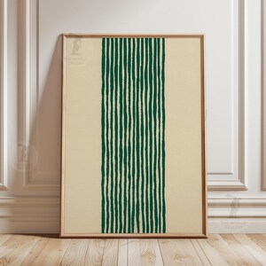 Peut inclure: Impression d'art encadrée avec un motif vertical de lignes vertes foncées sur un fond crème. L'œuvre est dans un cadre en bois et est exposée contre un mur blanc.