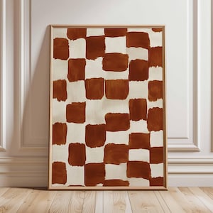 May include: A framed abstract art print with a repeating pattern of brown brushstrokes on a cream background. The artwork is displayed in a light wood frame, creating a modern aesthetic. The artwork is displayed on a wooden floor.
