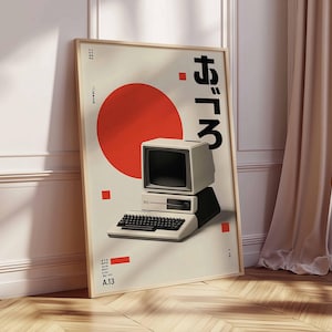 Puede incluir: Un p&oacute;ster enmarcado con un dise&ntilde;o de ordenador retro. La obra de arte incluye un c&iacute;rculo rojo, texto japon&eacute;s y un ordenador vintage con teclado. El p&oacute;ster est&aacute; sobre un fondo crema con un marco de madera.