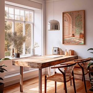 May include: A bright interior with a wooden desk and woven chairs. A large window offers a view of trees. A framed artwork hangs on the wall, and a modern pendant light hangs above the desk. Plants add a touch of nature to the room. The desk has metal legs.