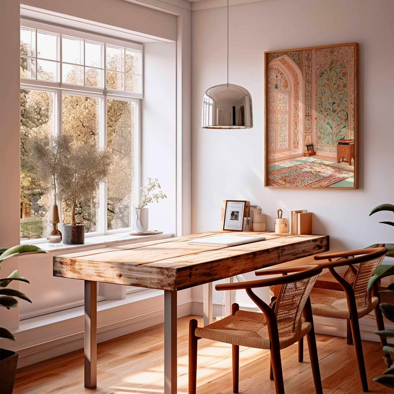 May include: A bright interior with a wooden desk and woven chairs. A large window offers a view of trees. A framed artwork hangs on the wall, and a modern pendant light hangs above the desk. Plants add a touch of nature to the room. The desk has metal legs.