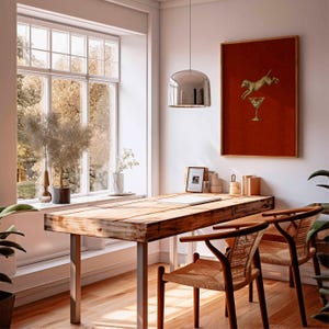 Pu&ograve; includere: Una stanza luminosa e ariosa con una scrivania in legno e due sedie. Un'opera d'arte incorniciata con un cane che salta sopra un bicchiere da cocktail &egrave; appesa alla parete. Una grande finestra offre una vista sugli alberi. Una lampada a sospensione argentata &egrave; appesa sopra la scrivania.
