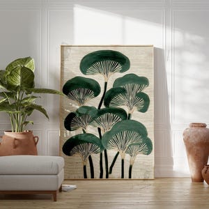 May include: A large framed art print featuring a stylized botanical design of dark green mushroom-like shapes on a beige background. The artwork is displayed in a room with a potted plant, a gray ottoman, and terracotta vases.