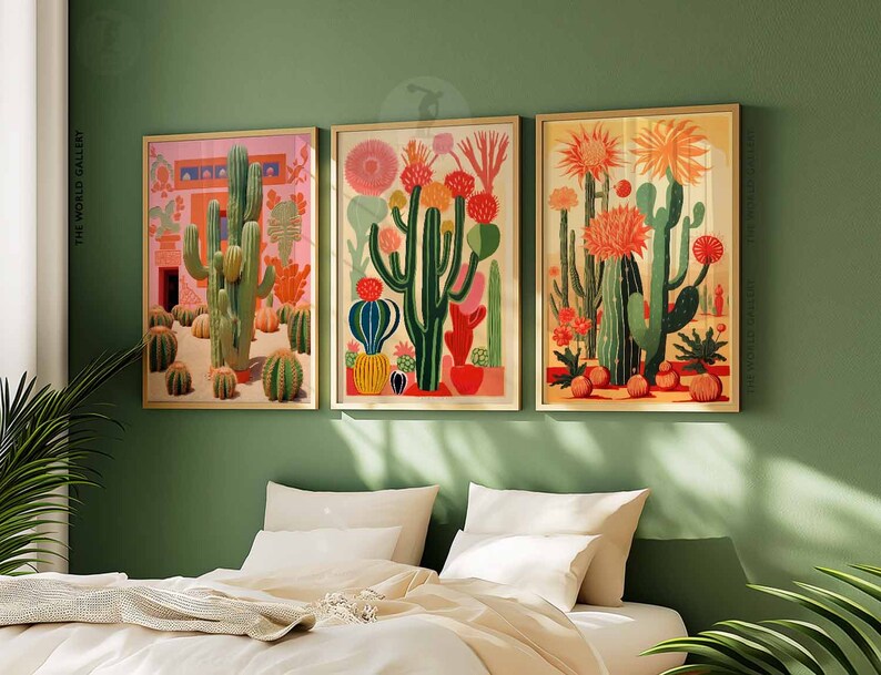 May include: Three framed illustrations of cacti in a variety of colors and styles. The cacti are set against a pink, green, and yellow background. The frames are a light wood color.