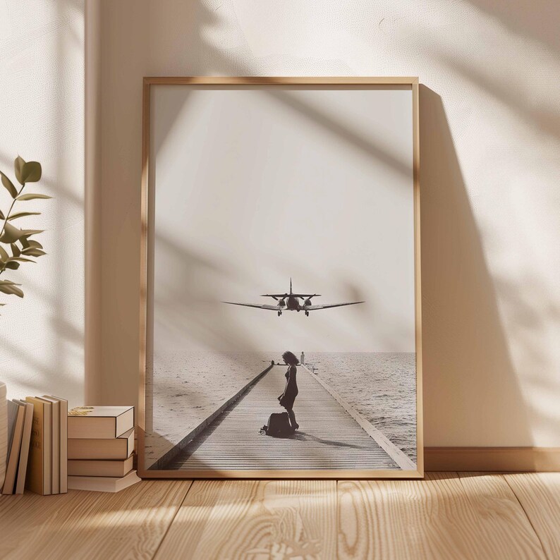 Puede incluir: Una impresi&oacute;n enmarcada en tonos sepia muestra a una mujer con equipaje en un muelle de madera, con un avi&oacute;n volando por encima. El muelle se extiende hacia el mar, con el cielo y el agua fusion&aacute;ndose en el fondo. La impresi&oacute;n est&aacute; en un marco de madera clara.