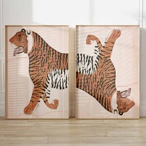 Peut inclure: Deux impressions encadr&eacute;es d'une illustration de tigre. Le tigre est repr&eacute;sent&eacute; dans un style traditionnel avec des rayures orange et noires sur un fond rose clair.