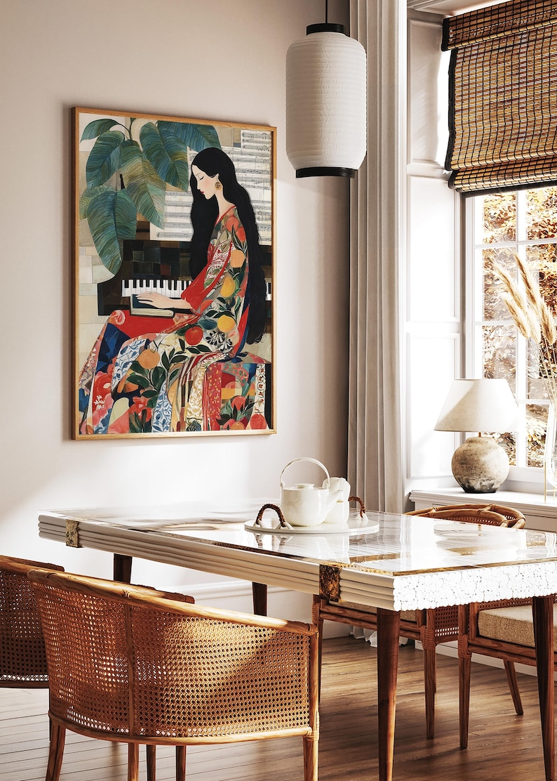 May include: A framed artwork shows a woman playing a piano, dressed in a vibrant patterned gown. The artwork is in a room with a white table, rattan chairs, and a window with a bamboo blind. A white paper lantern hangs from the ceiling.