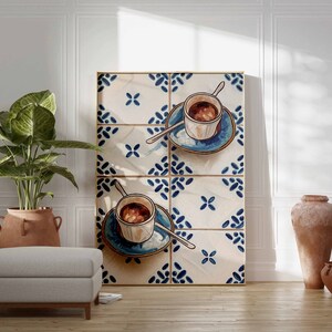May include: A framed print of two cups of coffee on blue and white patterned tiles. The cups are white with brown coffee and are on blue saucers.