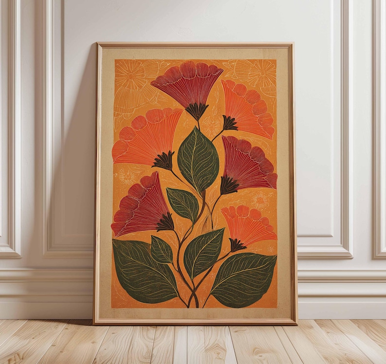 May include: Framed floral art print featuring stylized red and orange flowers with green leaves against an orange background. The artwork is in a wooden frame and leans against a white wall and wooden floor.