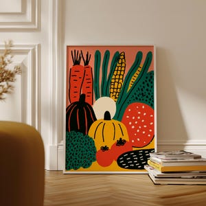 Könnte beinhalten: Ein gerahmter Kunstdruck mit einer farbenfrohen Illustration verschiedener Gemüsesorten. Das Kunstwerk zeigt orange Karotten, grünen Mais und Kürbisse in Schwarz und Gelb. Ein roter Hintergrund und ein weißer Rahmen vervollständigen das Design.