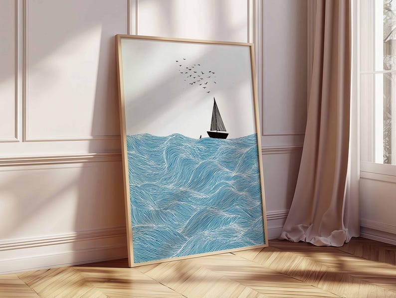 May include: A framed art print featuring a minimalist illustration of a sailboat on blue waves. The artwork includes a black sailboat, a flock of birds, and a light wood frame. The waves are detailed with white lines.