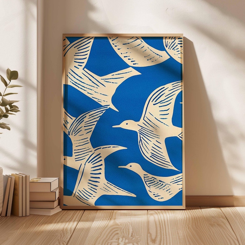 May include: A framed art print featuring a flock of cream-colored birds against a vibrant blue background. The birds are depicted in a stylized, linocut style, with detailed wing patterns. The artwork is encased in a simple wooden frame, suitable for wall decor.