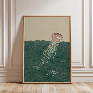 May include: A framed art print featuring a stylized illustration of a jellyfish in the ocean. The jellyfish is depicted in shades of red and white, with long, flowing tentacles. The ocean is rendered in dark green with wave patterns.