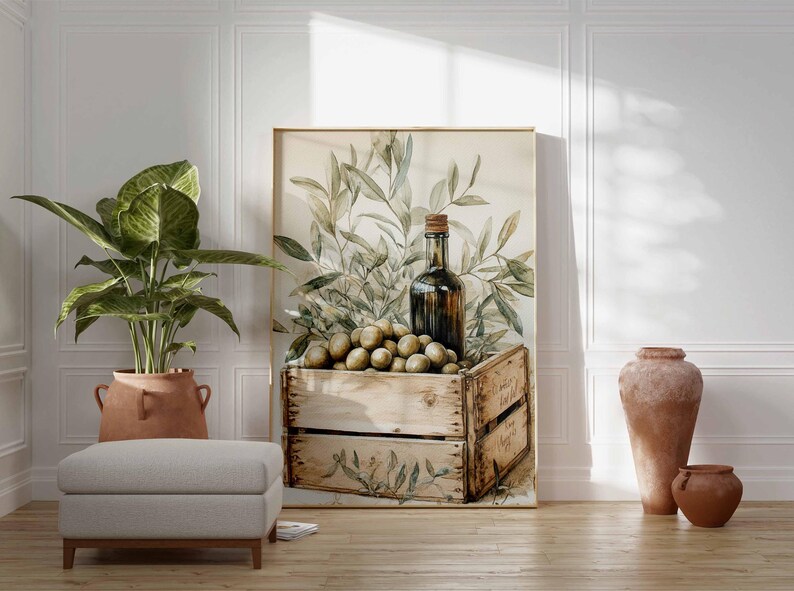 May include: A framed watercolor print featuring a wooden crate filled with olives, a dark glass bottle, and olive branches. The artwork is displayed in a room with a potted plant, a footstool, and terracotta vases.
