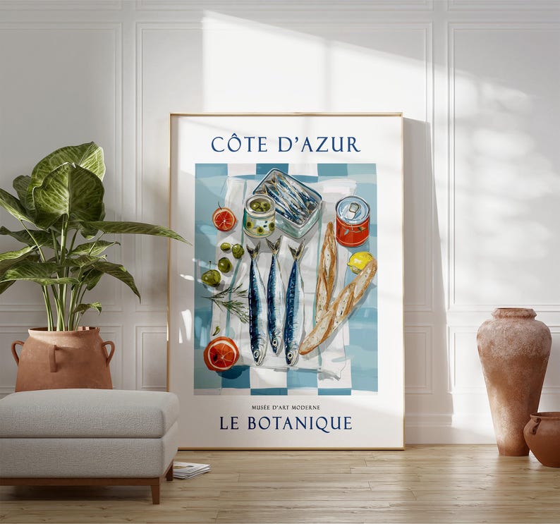 May include: A framed art print featuring a still life of sardines, olives, and bread on a blue and white checkered tablecloth. The print includes the text "C&Ocirc;TE D'AZUR" and "LE BOTANIQUE". The artwork has a vintage aesthetic.