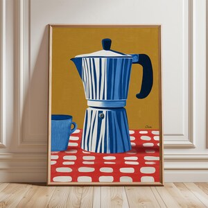 Puede incluir: Impresión artística enmarcada que presenta una cafetera italiana a rayas azules y blancas y una taza azul sobre una superficie con estampado rojo y blanco. El fondo es amarillo mostaza.