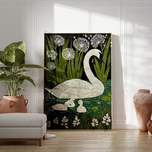May include: A framed art print featuring a white swan with two cygnets swimming in a pond, surrounded by green foliage and white dandelions. The artwork has a black background and is displayed in a room with a plant, ottoman, and decorative vases.