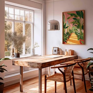 May include: A bright, airy room with a wooden desk and two chairs. A large window offers a view of trees. A framed botanical print hangs on the wall. A silver pendant light hangs above the desk. The room is decorated with plants.