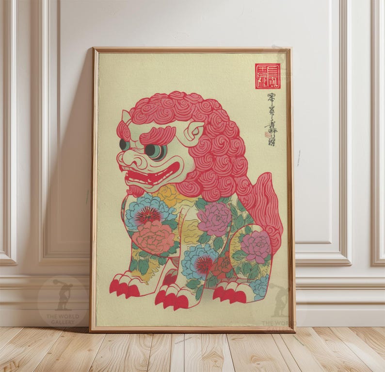 May include: Framed print of a colorful Foo Dog, a traditional guardian lion. The artwork features a red mane, floral patterns, and Japanese text. The print is in a gold frame and is displayed against a cream-colored background.