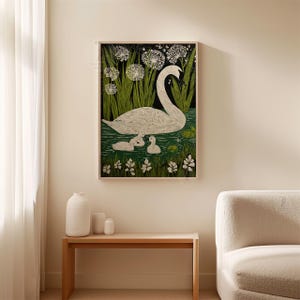 May include: Framed art print featuring a white swan with two cygnets swimming in a pond. The artwork has a black background with green reeds and white flowers. The swan and cygnets are white, and the water is green.