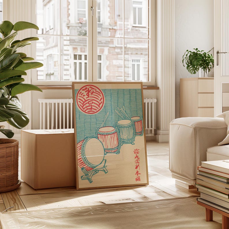 May include: A framed print featuring a traditional Japanese design. The artwork depicts several drums in red and turquoise, with a red circular emblem and Japanese text. The print is displayed in a light-colored wooden frame.