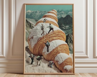 May include: A framed art print depicts a surreal scene of people climbing a giant croissant covered in snow, set against a backdrop of snow-capped mountains and a teal sky. The artwork is in a wooden frame.