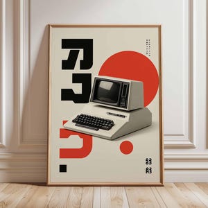 May include: A framed poster featuring a vintage computer design. The poster has a beige background with large black and red graphic elements, including the letters "RP" and a red circle. The computer is off-white with a black keyboard and screen.
