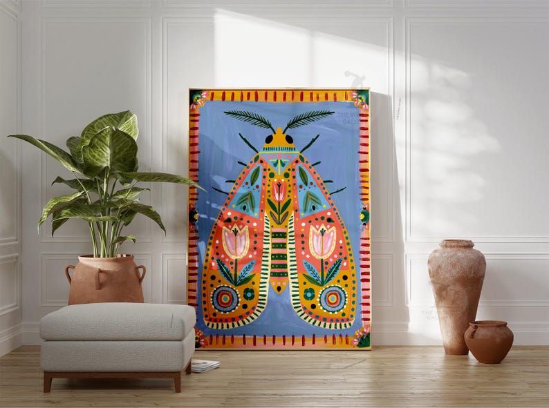 Pode incluir: Uma grande pintura colorida de uma mariposa com fundo azul. A mariposa tem padr&otilde;es intrincados em laranja, amarelo e azul-petr&oacute;leo. A pintura &eacute; emoldurada em uma borda amarela e vermelha. Uma planta em vaso, um pufe e vasos est&atilde;o em primeiro plano.