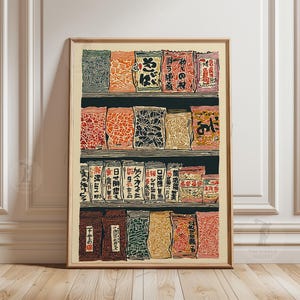 Op de afbeelding: Een ingelijste prent met een vintage Japanse houtsnede van verpakte goederen op planken. De prent toont diverse kleurrijke verpakkingen met Japanse tekst, gerangschikt op drie planken. Het kunstwerk is geplaatst tegen een neutrale achtergrond, ingelijst in een houten lijst.