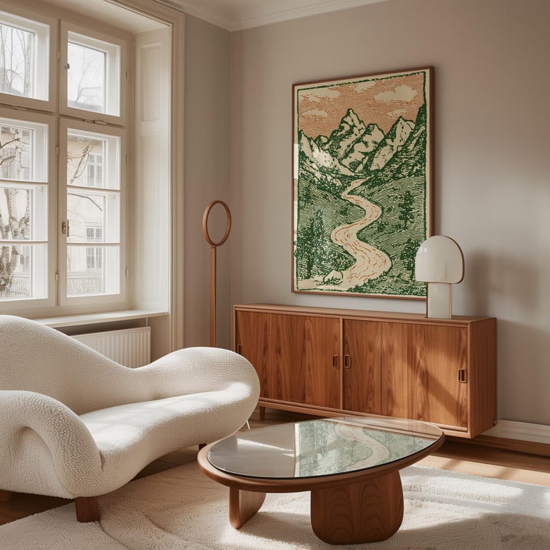 May include: A living room scene featuring a cream-colored, curved sofa, a wooden coffee table with a glass top, and a wooden cabinet. A framed landscape art piece with green and beige tones hangs above the cabinet. A white lamp and a wooden floor lamp are also present.