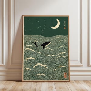 Könnte beinhalten: Gerahmter Kunstdruck, der einen Wal zeigt, der aus dem Meer unter einem Halbmond und Sternen springt. Das Kunstwerk hat einen minimalistischen Stil mit einem dunkelgrünen Hintergrund und weißen und schwarzen Akzenten, ähnlich japanischen Holzschnitten.