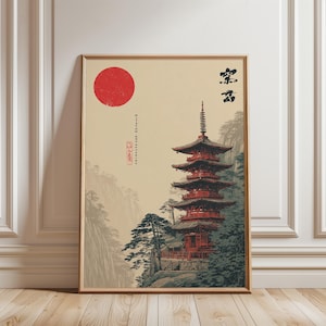 Peut inclure: Impression encadrée représentant une pagode japonaise avec un soleil rouge. La pagode est rouge et marron, sur fond de montagnes et d'arbres. Caractères et texte japonais visibles.