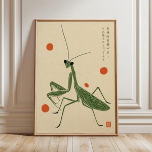 May include: A framed wall art print on a light beige background featuring a green praying mantis with a dotted texture. The composition includes four small red circles and vertical Japanese text in the upper right corner, with a red square seal.