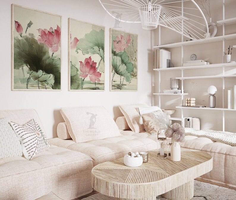 May include: Three framed watercolor paintings of lotus flowers in shades of pink and green hang above a light-colored sectional sofa. A wooden coffee table and decorative pillows complete the living room setting.
