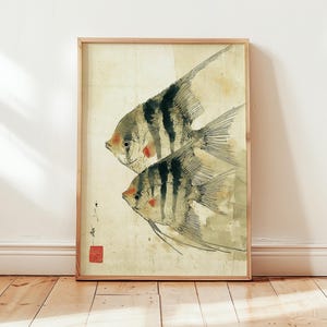 K&ouml;nnte beinhalten: Gerahmter Kunstdruck mit zwei stilisierten Fischen mit schwarzen Streifen und roten Akzenten. Das Kunstwerk hat eine Vintage-&Auml;sthetik mit beigem Hintergrund und Holzrahmen. Die Fische sind in einem traditionellen japanischen Stil dargestellt.