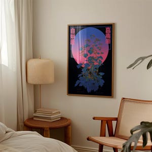 May include: A framed art print featuring a stylized floral design with a gradient background of pink, blue, and black. The artwork includes Japanese text on the sides and is displayed in a room with a lamp and chair.