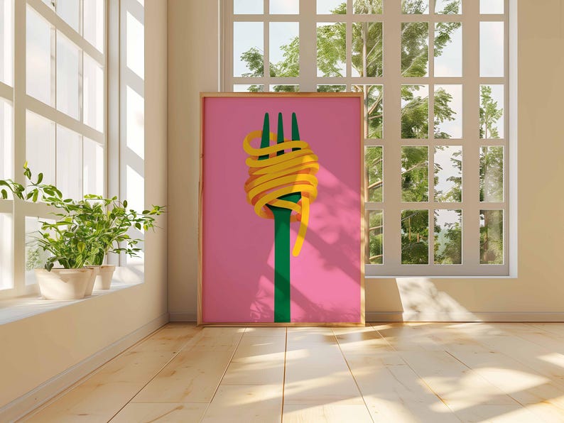 Op de afbeelding: Een ingelijste kunstprint met een groene vork met gele spaghetti op een roze achtergrond. Het kunstwerk staat in een kamer met een raam en planten.