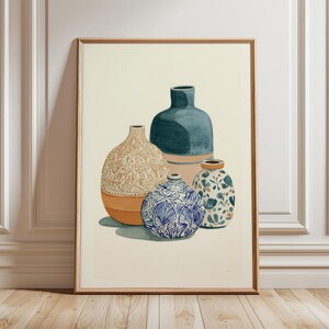 Op de afbeelding: Een ingelijste kunstdruk met een stilleven van vier decoratieve vazen. De vazen zijn in tinten blauw, oranje en beige, met ingewikkelde patronen en texturen. Het kunstwerk wordt gepresenteerd op een lichte achtergrond.