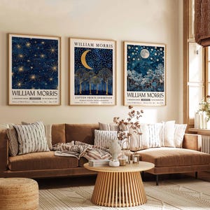 Op de afbeelding: Drie ingelijste prints met een blauw en gouden kleurenschema met een maan en sterren. De prints zijn getiteld "William Morris" en hangen aan een beige muur boven een bruine hoekbank.