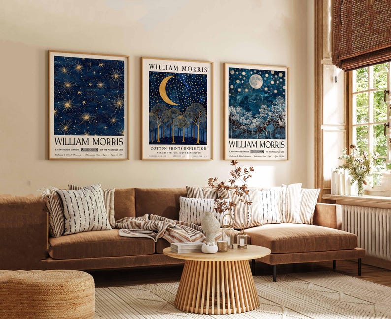 Op de afbeelding: Drie ingelijste prints met een blauw en gouden kleurenschema met een maan en sterren. De prints zijn getiteld "William Morris" en hangen aan een beige muur boven een bruine hoekbank.