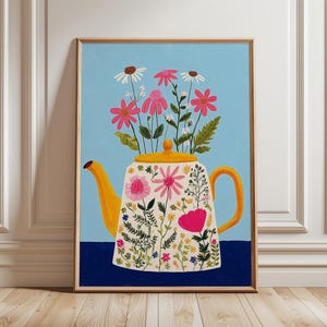 以下が含まれることがあります： 黄色いティーポットにピンクと白の花が描かれた、額入りのアートプリント。ティーポットは花柄で装飾され、明るい青色の背景に濃い青色のベースが配置され、鮮やかな構図を作り出しています。